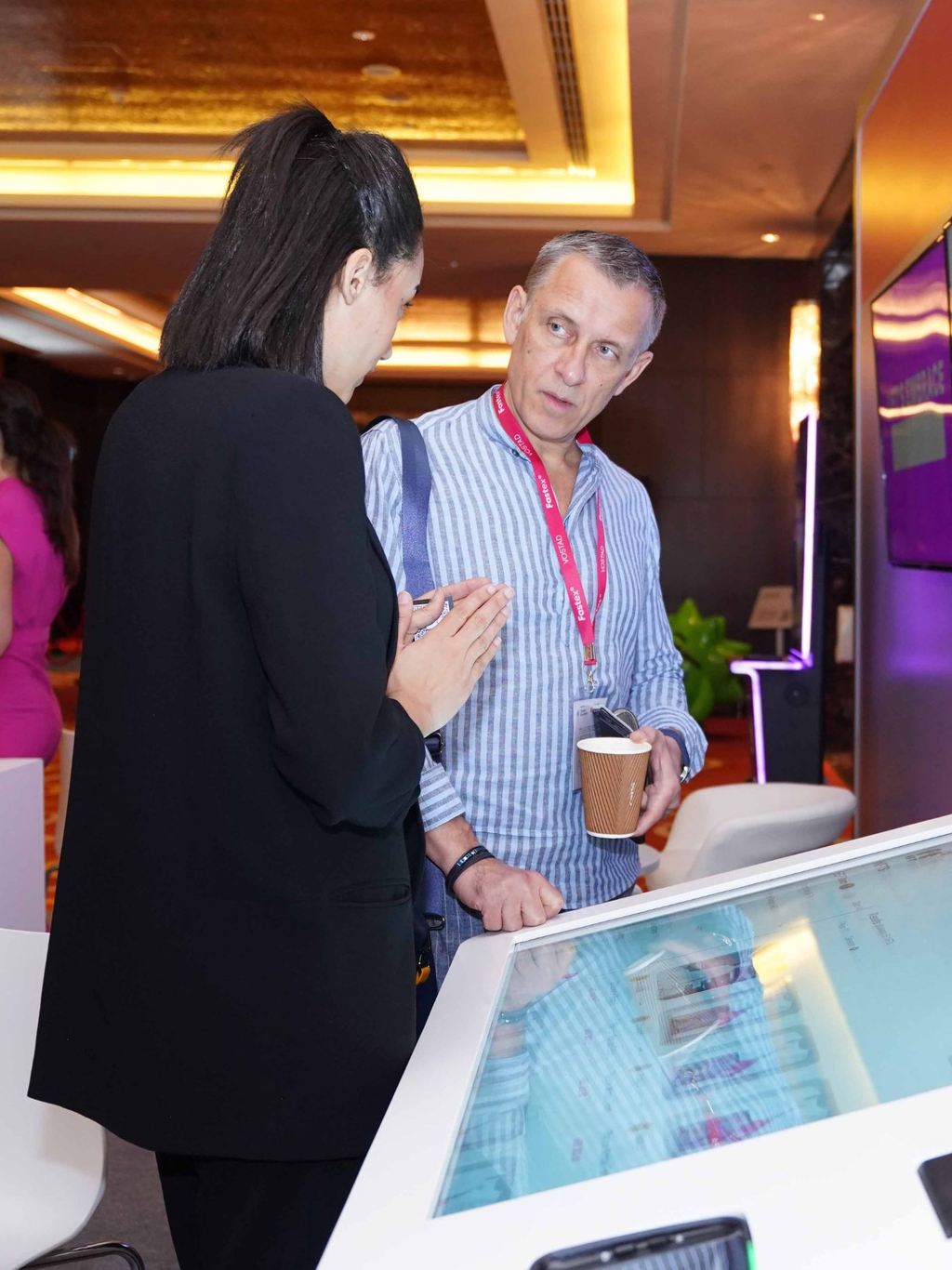 Two delegates talking beside a touchscreen display at a conference